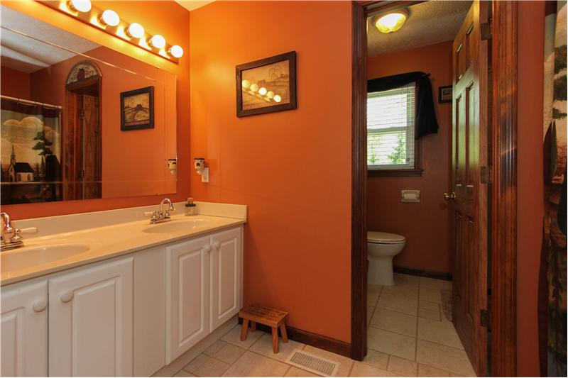 Hall bathroom, sinks and tub on one side & toilet & shower behind the door.