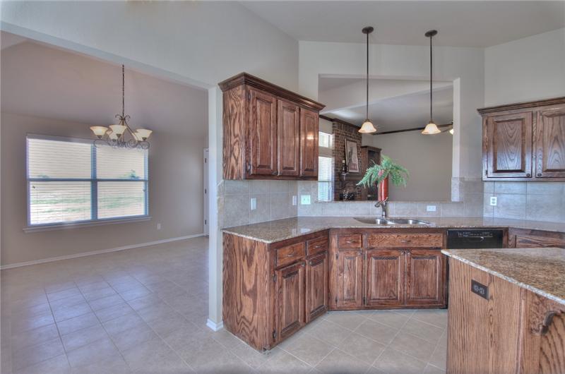 GRANITE, DARK STAIN WOOD CABINETS, TILED BACKSPLASH