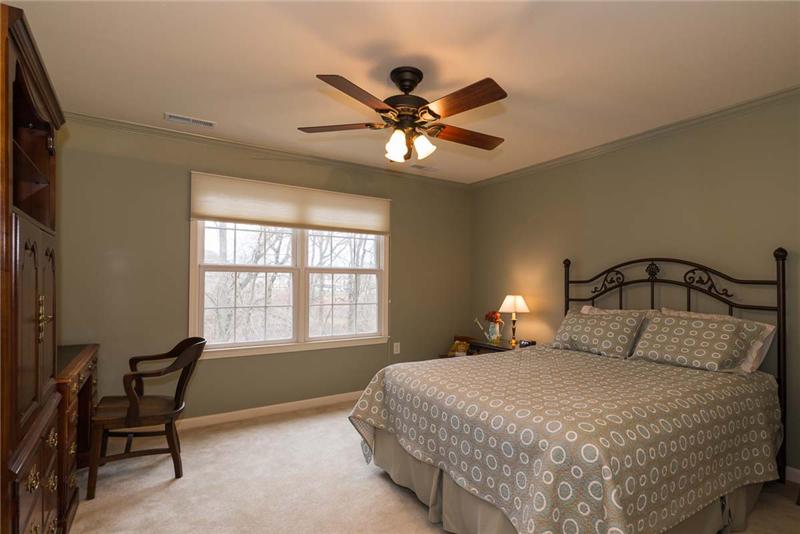 Large second bedroom with lighted ceiling fan overlooks the rear wooded area.
