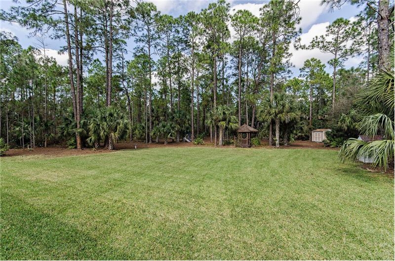 huge manicured lawn with a gazebo and storage sheds